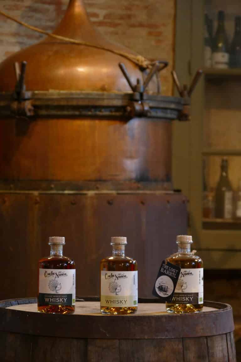 3 bouteilles de whisky devant l'alambic